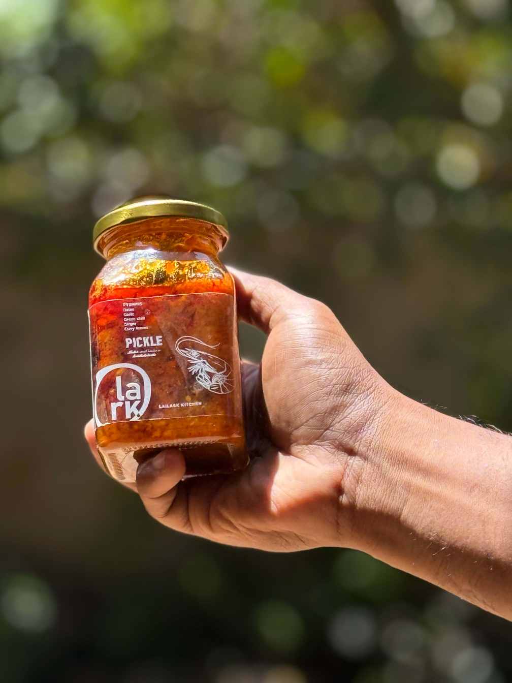A jar of Lailark prawns and dates pickle, held in one hand.